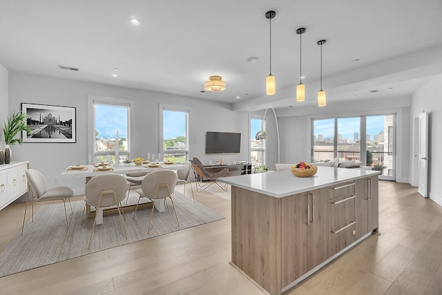 kitchen with decorative light fixtures, a center island, and light wood-type flooring