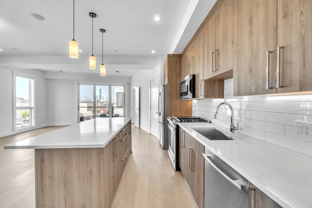 kitchen with stove, light hardwood / wood-style flooring, hanging light fixtures, dishwashing machine, and a center island