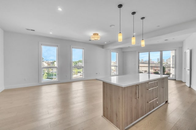 kitchen with a kitchen island, light hardwood / wood-style flooring, hanging light fixtures, and a wealth of natural light