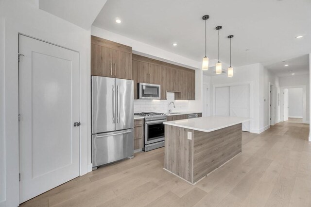 kitchen with a center island, light hardwood / wood-style floors, hanging light fixtures, and appliances with stainless steel finishes