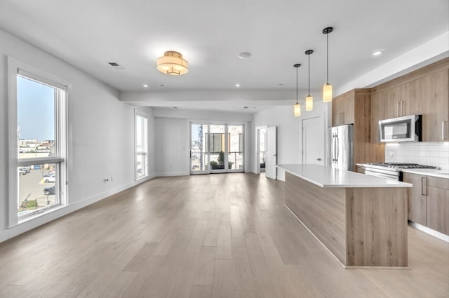 kitchen with tasteful backsplash, stainless steel appliances, plenty of natural light, a kitchen island, and light hardwood / wood-style flooring