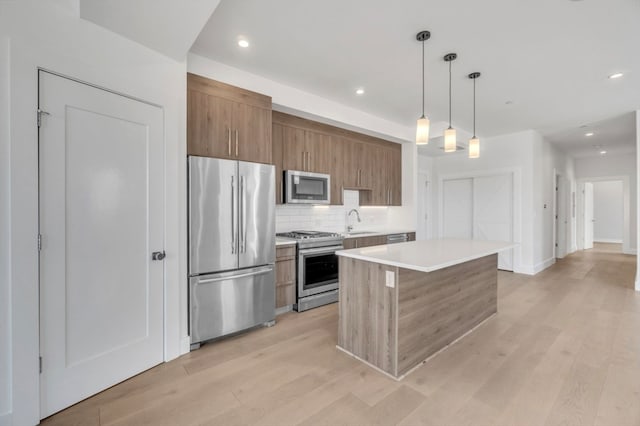 kitchen featuring appliances with stainless steel finishes, light hardwood / wood-style flooring, tasteful backsplash, sink, and hanging light fixtures