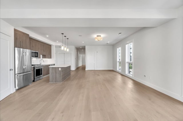 kitchen featuring appliances with stainless steel finishes, light hardwood / wood-style flooring, pendant lighting, and a kitchen island