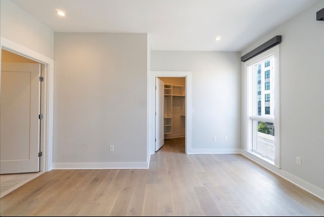 unfurnished bedroom featuring a closet, light wood-type flooring, and a walk in closet