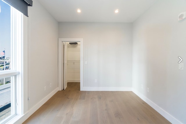 unfurnished bedroom with light hardwood / wood-style flooring, a closet, and a walk in closet