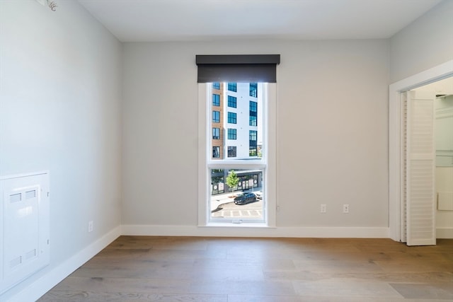 unfurnished room featuring wood-type flooring, heating unit, and plenty of natural light