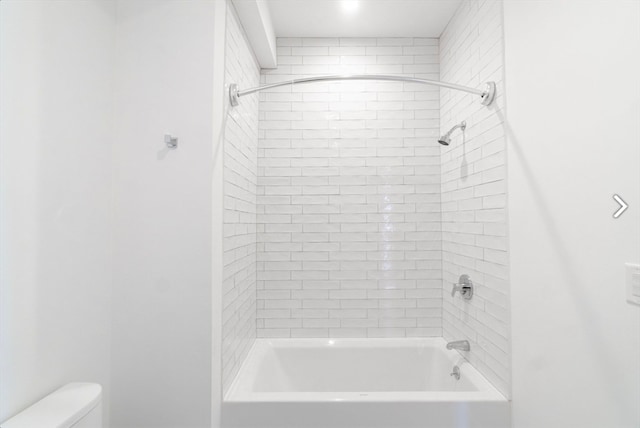 bathroom featuring tiled shower / bath and toilet