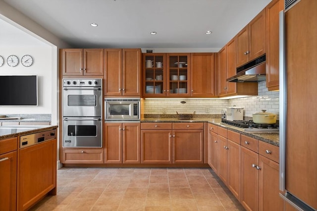 kitchen featuring light tile patterned floors, stainless steel appliances, tasteful backsplash, and dark stone countertops