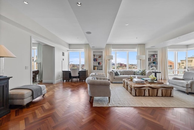 living room featuring parquet flooring, built in features, and a healthy amount of sunlight