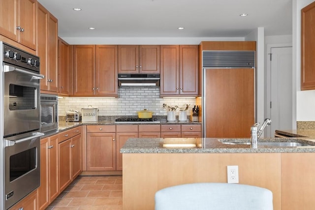 kitchen with light stone countertops, decorative backsplash, and stainless steel appliances