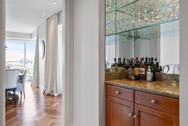 bar featuring stone countertops and light parquet flooring