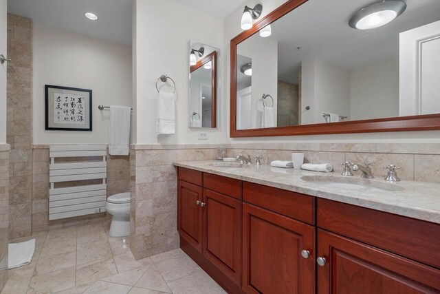 bathroom with tile patterned flooring, vanity, toilet, and tile walls