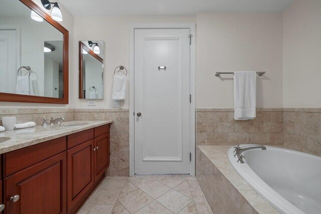 bathroom featuring tile patterned flooring, vanity, and tiled bath