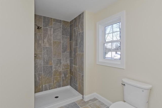 bathroom featuring a tile shower, tile patterned flooring, and toilet