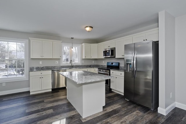 kitchen featuring sink, a center island, hanging light fixtures, appliances with stainless steel finishes, and white cabinets