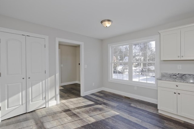 unfurnished dining area featuring dark wood-type flooring