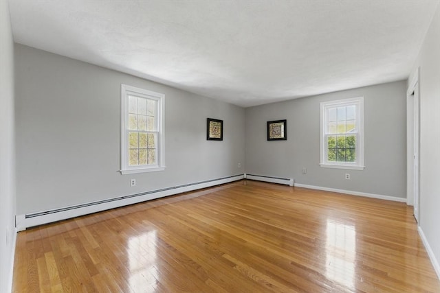 spare room featuring light wood-type flooring, a baseboard radiator, baseboards, and baseboard heating