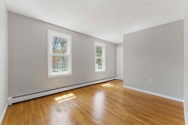 unfurnished room featuring baseboard heating, light wood finished floors, and baseboards