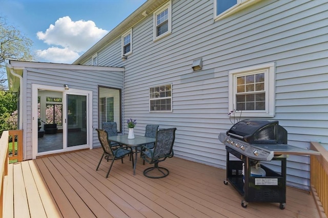 wooden terrace with outdoor dining space and a grill