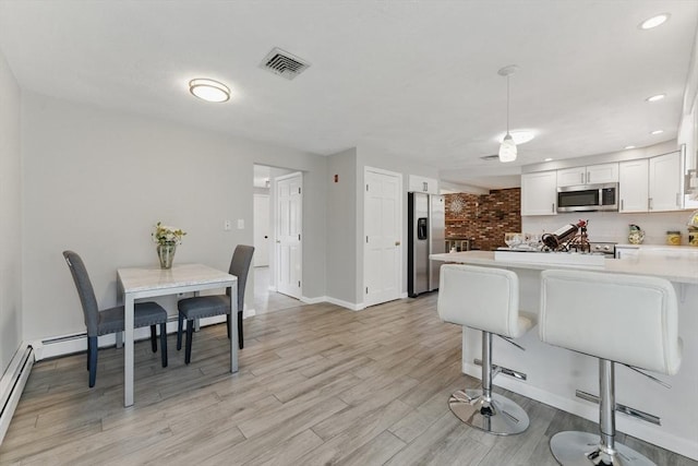 kitchen featuring stainless steel appliances, light countertops, light wood finished floors, white cabinetry, and baseboards