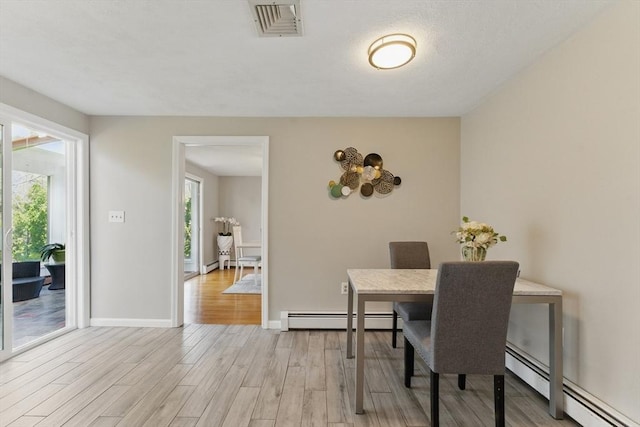 dining room featuring a baseboard radiator, light wood-style flooring, and baseboards