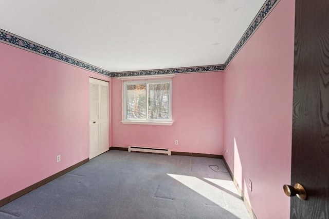 carpeted empty room with a baseboard heating unit