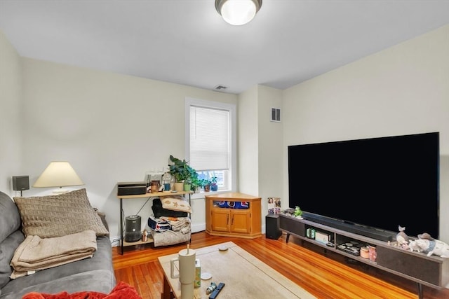 living room featuring visible vents, baseboard heating, and wood finished floors