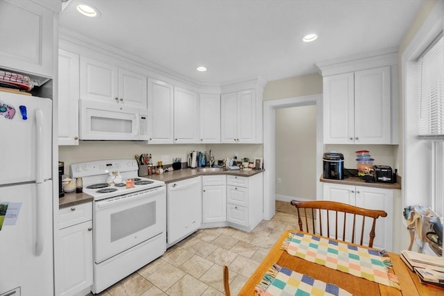 kitchen with white appliances, dark countertops, recessed lighting, and white cabinets