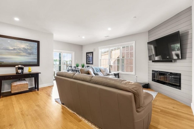 living area featuring light wood-type flooring, a large fireplace, baseboards, and recessed lighting