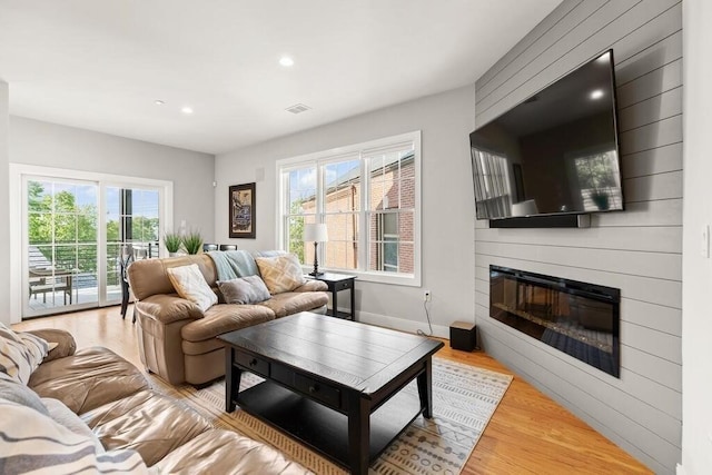 living area featuring light wood finished floors, baseboards, visible vents, a fireplace, and recessed lighting