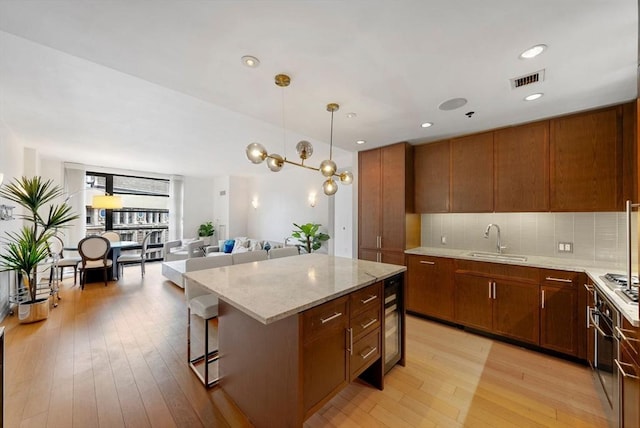 580 Washington St Unit 901, Boston, MA 02111 - kitchen with a sink, light wood-style flooring, light stone counters, tasteful backsplash, and a kitchen island