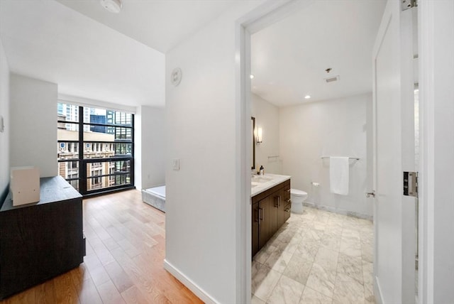 580 Washington St Unit 901, Boston, MA 02111 - bathroom featuring vanity, toilet, baseboards, and wood finished floors