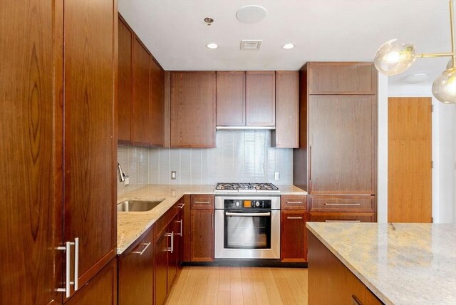580 Washington St Unit 901, Boston, MA 02111 - kitchen featuring oven, a sink, gas stovetop, backsplash, and light stone counters