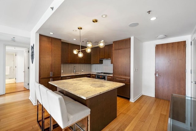 580 Washington St Unit 901, Boston, MA 02111 - kitchen featuring a sink, backsplash, baseboards, light wood-style flooring, and a kitchen island