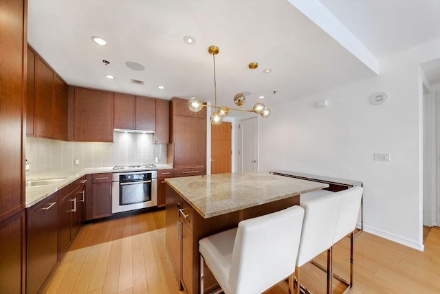 580 Washington St Unit 901, Boston, MA 02111 - kitchen featuring appliances with stainless steel finishes, a kitchen island, light wood-type flooring, light stone counters, and recessed lighting
