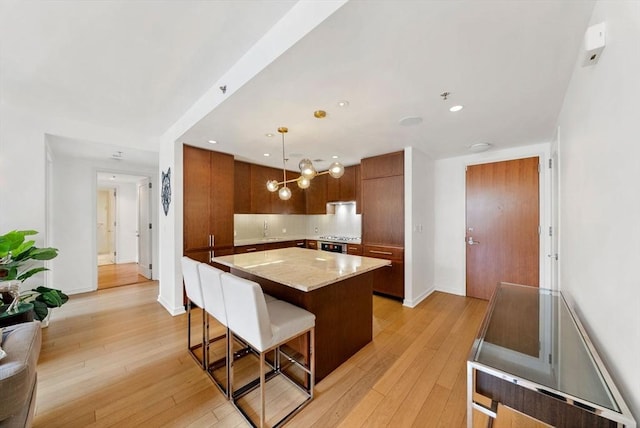 580 Washington St Unit 901, Boston, MA 02111 - kitchen with a kitchen breakfast bar, light wood finished floors, a center island, decorative light fixtures, and recessed lighting