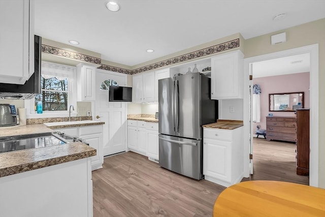 kitchen featuring light hardwood / wood-style floors, white cabinetry, and stainless steel refrigerator