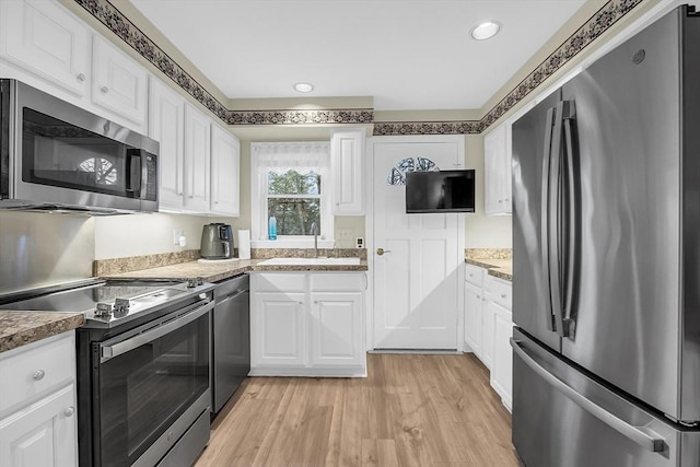 kitchen featuring white cabinets, sink, stainless steel appliances, and light hardwood / wood-style flooring