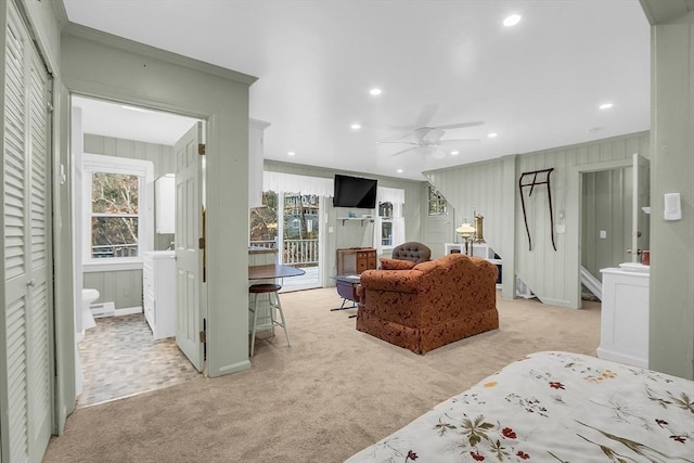 carpeted bedroom with access to exterior, ceiling fan, wooden walls, and ornamental molding