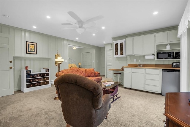 living room featuring ceiling fan, light colored carpet, and sink