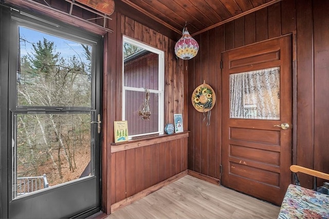 doorway with wooden ceiling, wooden walls, and light hardwood / wood-style flooring