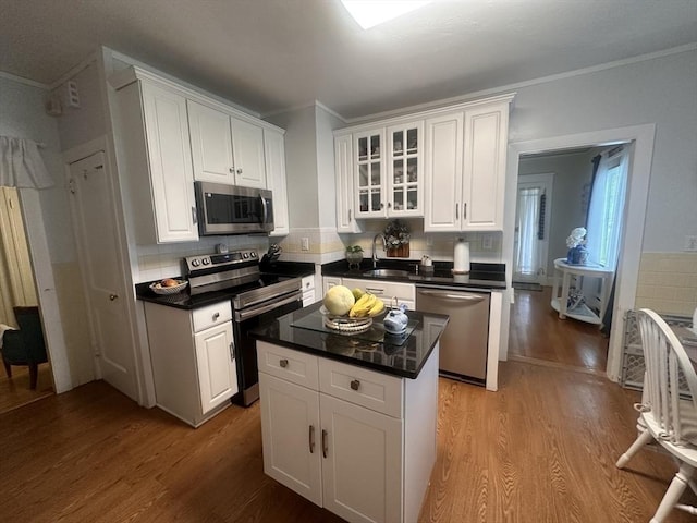 kitchen with white cabinetry, a kitchen island, light hardwood / wood-style flooring, and appliances with stainless steel finishes