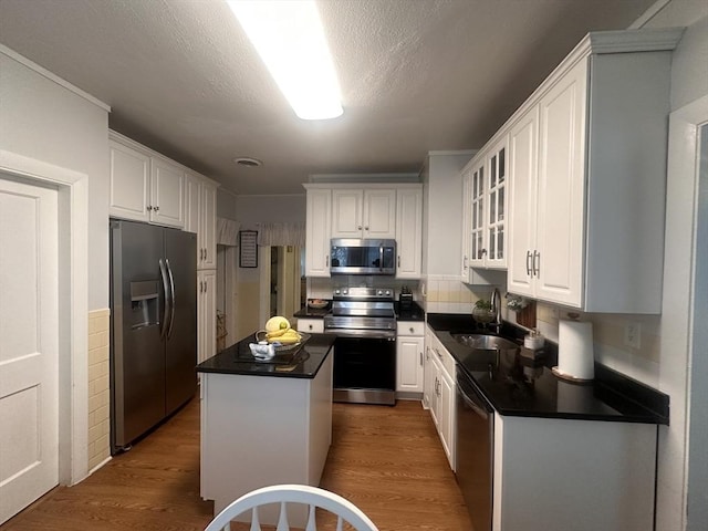 kitchen with a kitchen island, sink, white cabinets, dark hardwood / wood-style flooring, and stainless steel appliances