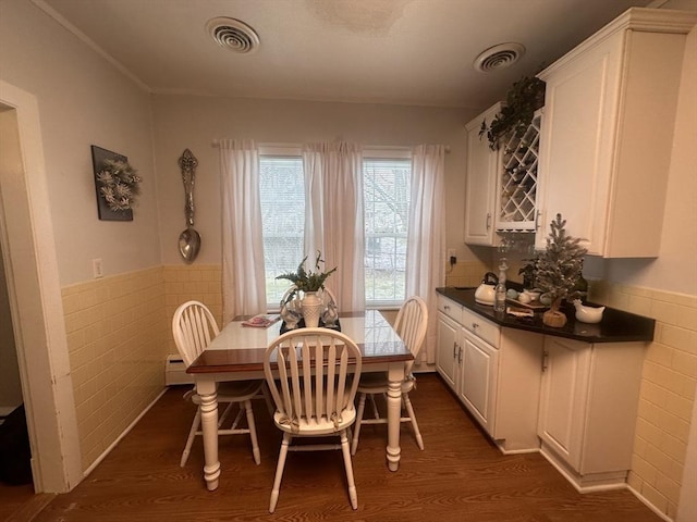 dining room featuring tile walls and dark wood-type flooring