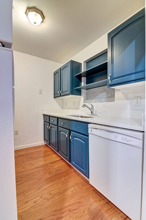 kitchen with blue cabinetry, light hardwood / wood-style floors, sink, and white appliances