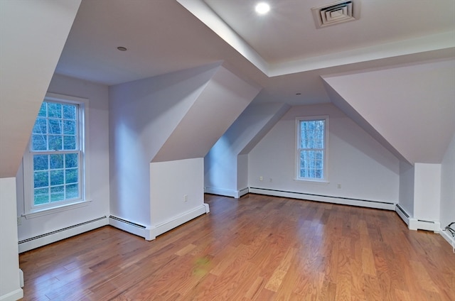 bonus room featuring a baseboard heating unit, light hardwood / wood-style flooring, and vaulted ceiling