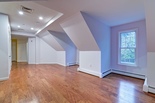 additional living space with light hardwood / wood-style floors and a baseboard heating unit