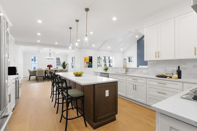 7 Bennett St, Natick, MA 01760 - kitchen featuring light wood-style floors, a center island, light countertops, a breakfast bar area, and beamed ceiling