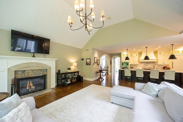 5 Copperbeech Cir, Westborough, MA 01581 - living room with dark wood-style floors, a chandelier, arched walkways, a fireplace, and high vaulted ceiling