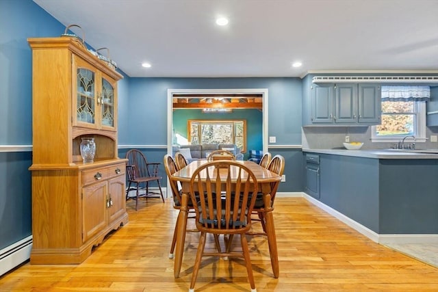 dining room with a healthy amount of sunlight, light wood-style flooring, and baseboard heating